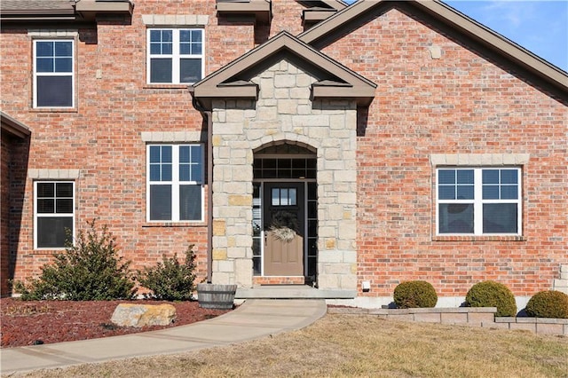 entrance to property featuring stone siding and brick siding