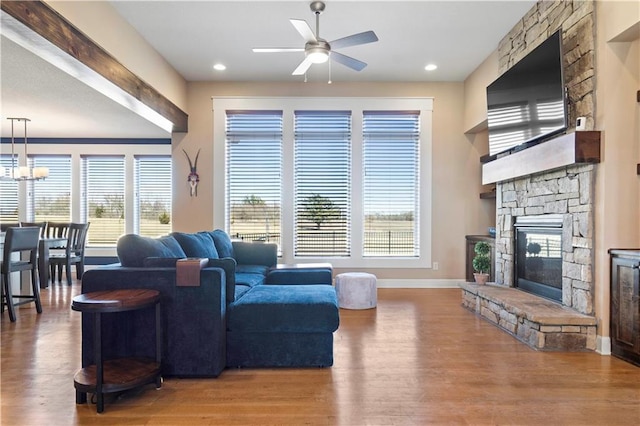 living area with a wealth of natural light, wood finished floors, and a stone fireplace