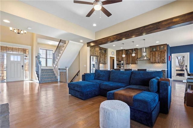 living room featuring stairs, ceiling fan with notable chandelier, wood finished floors, and recessed lighting