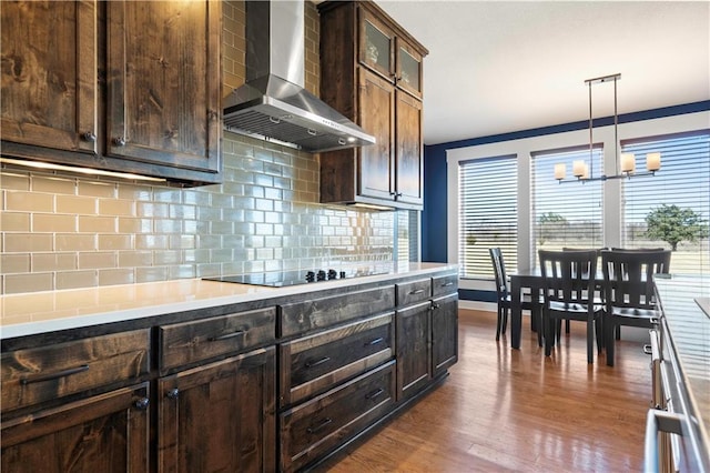 kitchen with dark brown cabinetry, wall chimney exhaust hood, decorative backsplash, and dark wood-type flooring