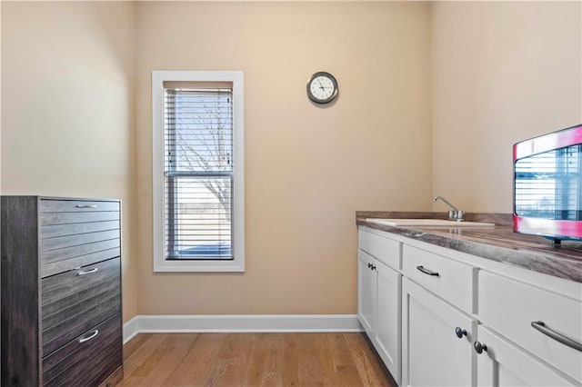 laundry room featuring light wood-style flooring, baseboards, and a sink