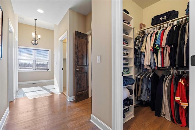 walk in closet featuring a chandelier and wood finished floors