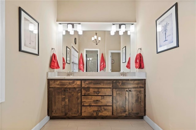 full bath with double vanity, an inviting chandelier, baseboards, and a sink