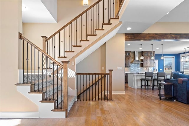 stairs with recessed lighting, baseboards, a high ceiling, and wood finished floors