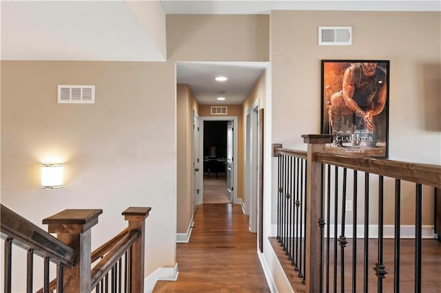 hallway with wood finished floors, an upstairs landing, and visible vents