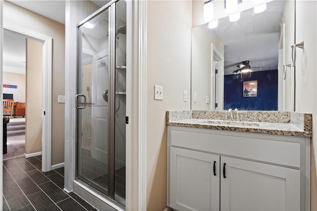 bathroom with wood finish floors, a stall shower, vanity, and baseboards