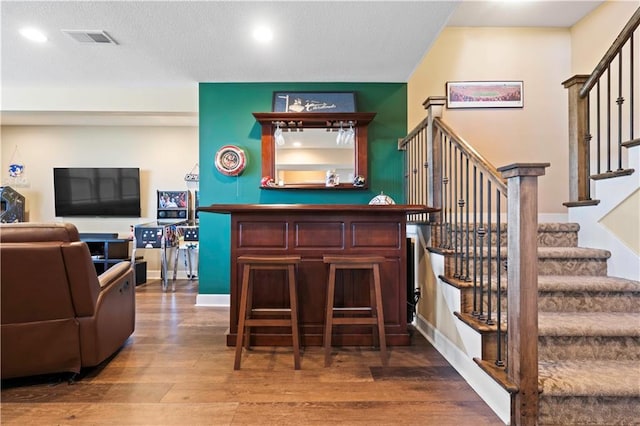 bar with recessed lighting, visible vents, stairway, a bar, and wood finished floors