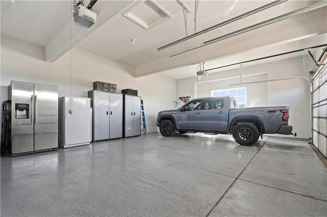 parking garage featuring freestanding refrigerator, a garage door opener, and stainless steel fridge with ice dispenser