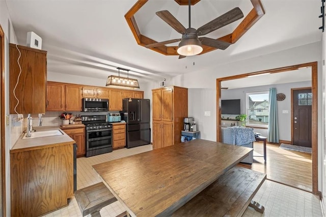 kitchen featuring ceiling fan, appliances with stainless steel finishes, brown cabinets, light countertops, and a sink