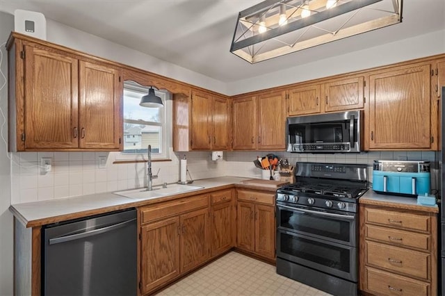 kitchen featuring light floors, light countertops, backsplash, appliances with stainless steel finishes, and a sink