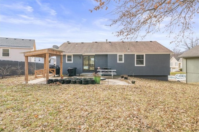 rear view of house with roof with shingles, fence, and a patio