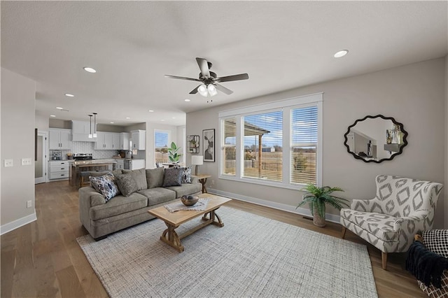 living room with dark wood-type flooring, recessed lighting, ceiling fan, and baseboards