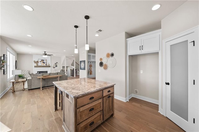 16967 S Hunter St, Olathe, KS 66062 - kitchen with light wood-type flooring, a fireplace, a center island, and white cabinets