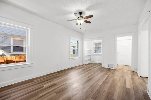 interior space with a ceiling fan, baseboards, and wood finished floors