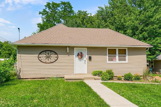 view of front of home with a shingled roof and a front yard