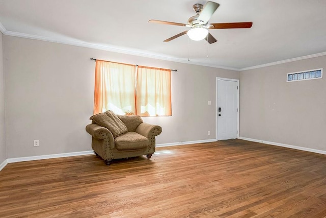 sitting room with baseboards, visible vents, a ceiling fan, ornamental molding, and wood finished floors