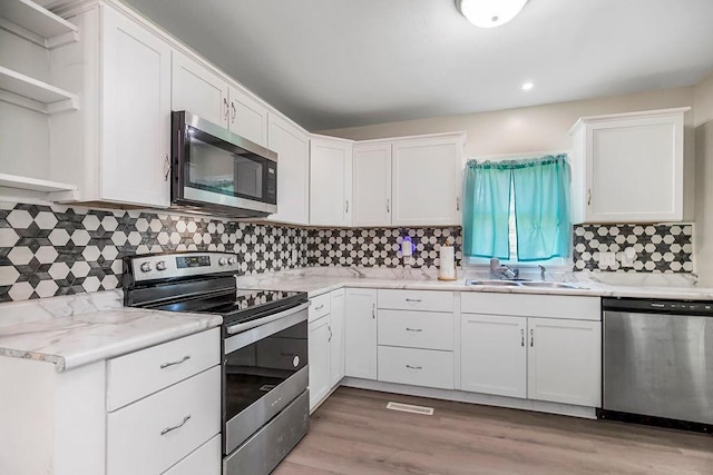 kitchen featuring white cabinets, appliances with stainless steel finishes, light countertops, open shelves, and backsplash