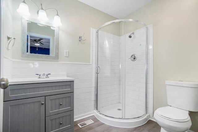 full bathroom featuring a stall shower, visible vents, toilet, wood finished floors, and tile walls