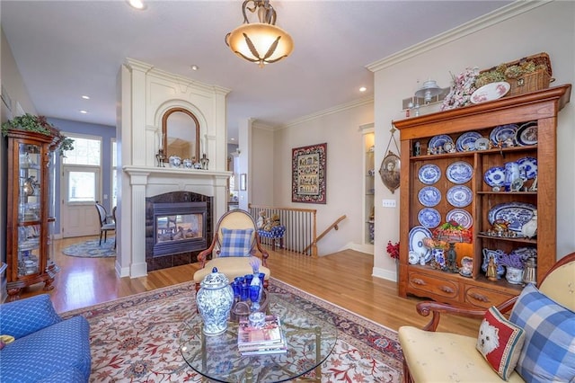 living room featuring ornamental molding, a tile fireplace, baseboards, and wood finished floors