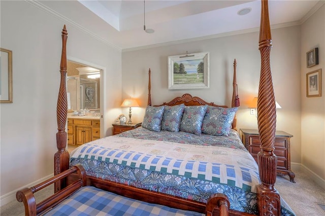 carpeted bedroom with a tray ceiling, ornamental molding, ensuite bath, and baseboards