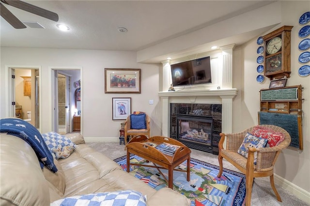 living room with a ceiling fan, carpet, baseboards, and a tiled fireplace