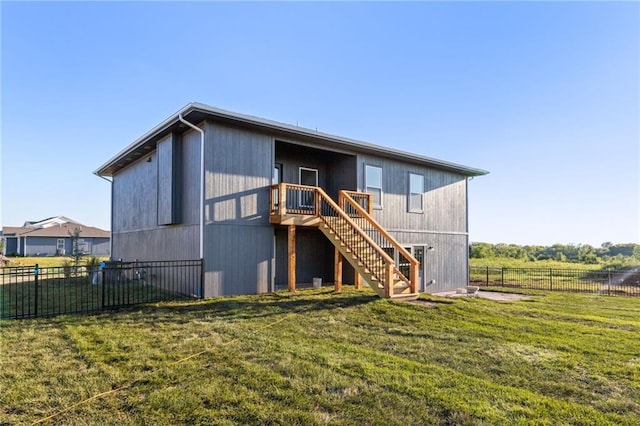 rear view of house with fence, stairway, and a lawn