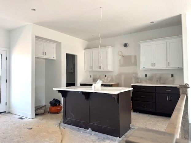 kitchen featuring white cabinetry, a breakfast bar, light countertops, and a center island