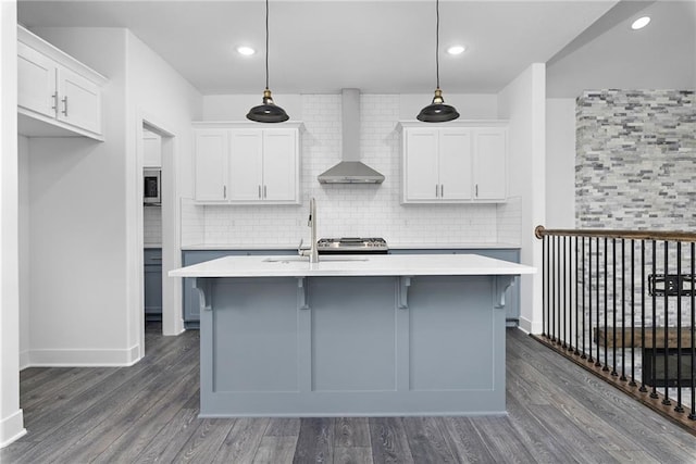 kitchen with dark wood-style floors, wall chimney exhaust hood, a sink, and light countertops