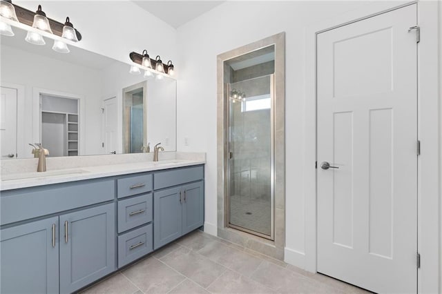 full bath with tile patterned flooring, a sink, a spacious closet, double vanity, and a stall shower