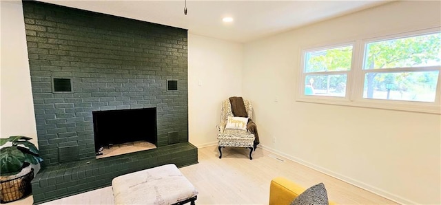 living area featuring a brick fireplace, light wood-style flooring, baseboards, and recessed lighting