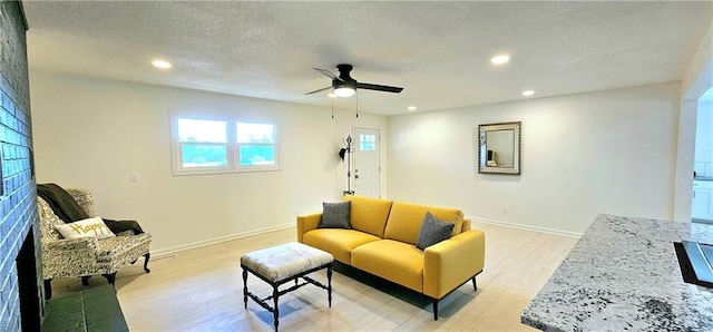 living area with light wood-style floors, baseboards, a textured ceiling, and recessed lighting