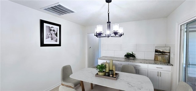 dining space featuring visible vents, a notable chandelier, and baseboards