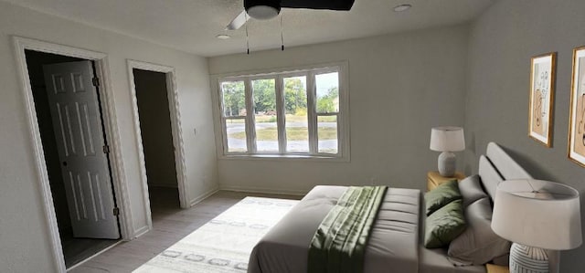 bedroom with light wood-type flooring, baseboards, and a ceiling fan