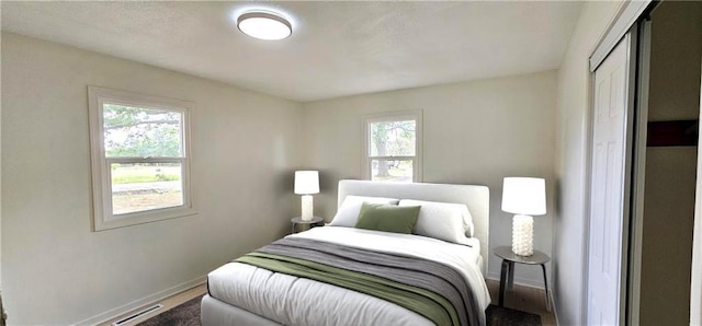 bedroom with a closet, multiple windows, visible vents, and baseboards