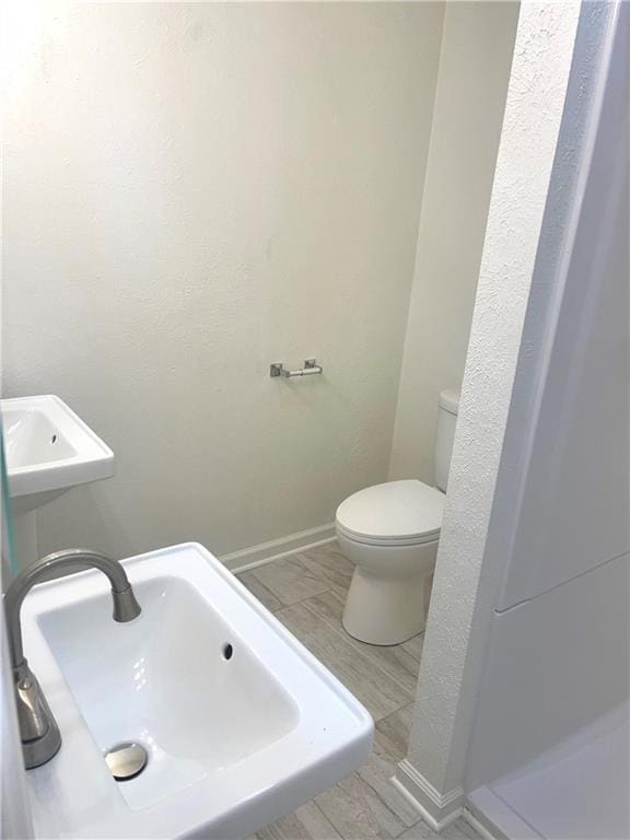 bathroom with a sink, toilet, and baseboards