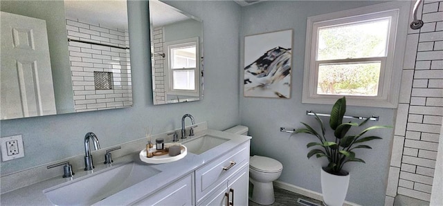 full bath with toilet, double vanity, visible vents, and a sink