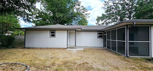 rear view of property with a sunroom, a chimney, and fence