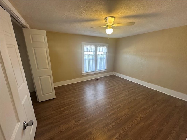 spare room with baseboards, dark wood-type flooring, a ceiling fan, and a textured ceiling