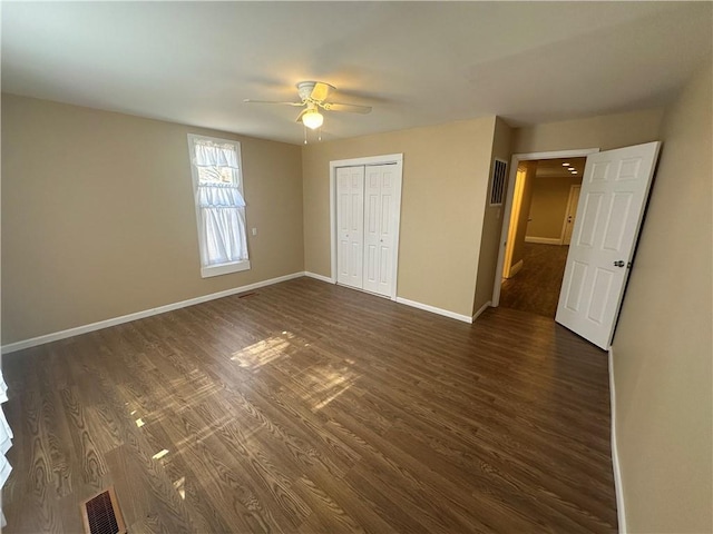 unfurnished bedroom featuring dark wood-type flooring, visible vents, baseboards, and a closet