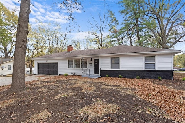 ranch-style home with an attached garage, driveway, a chimney, and brick siding