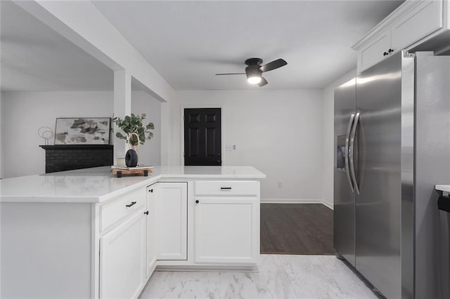 kitchen with marble finish floor, stainless steel fridge with ice dispenser, white cabinetry, ceiling fan, and baseboards