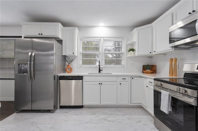 kitchen with light countertops, appliances with stainless steel finishes, a sink, and white cabinetry