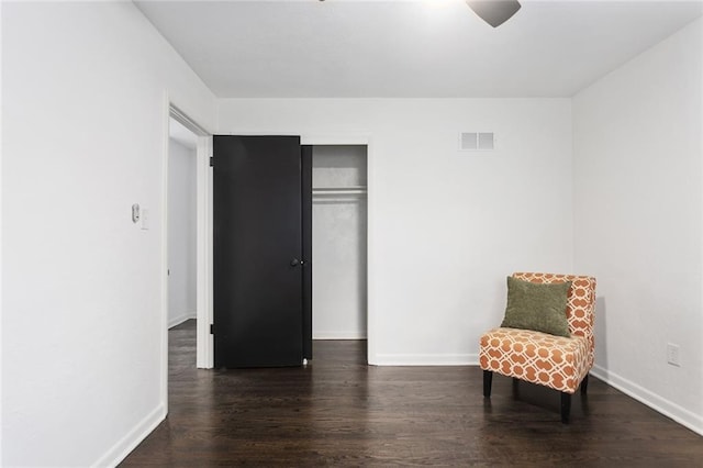 living area with dark wood-type flooring, visible vents, and baseboards