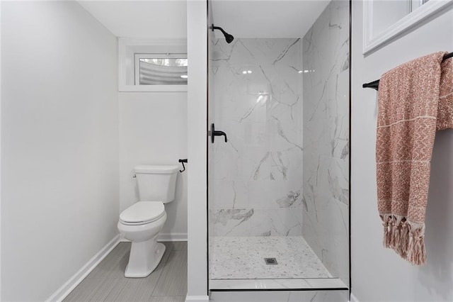 full bath featuring toilet, a marble finish shower, and baseboards