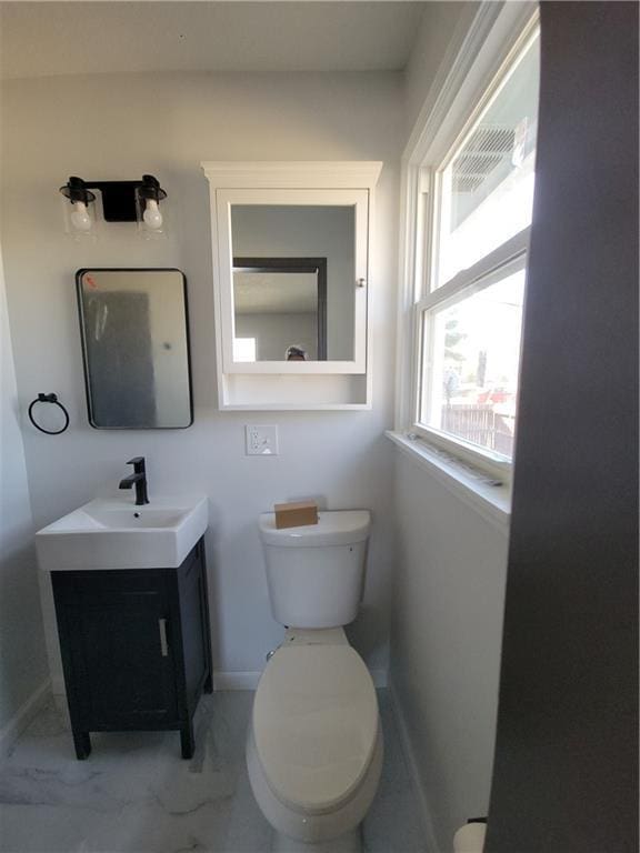 half bath with baseboards, marble finish floor, vanity, and toilet