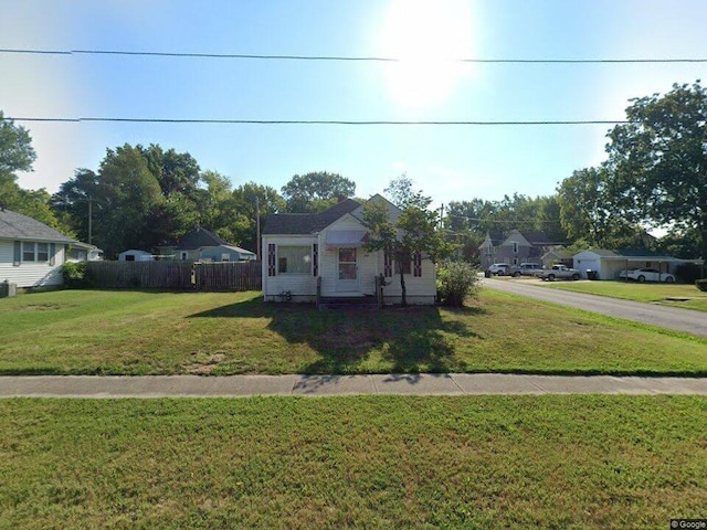 bungalow-style home featuring a front lawn and fence