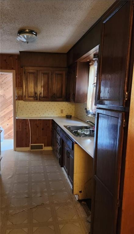 kitchen with light floors, a sink, light countertops, and wooden walls