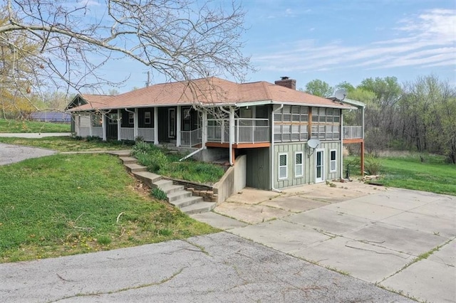 24722 Tonganoxie Dr, Leavenworth, KS 66048 - view of front facade with board and batten siding, a sunroom, a chimney, and a front yard