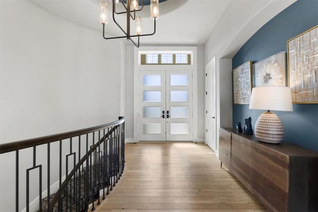 entrance foyer featuring an inviting chandelier, baseboards, hardwood / wood-style floors, and french doors