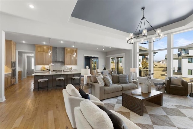 living room with light wood-style floors, recessed lighting, and a notable chandelier